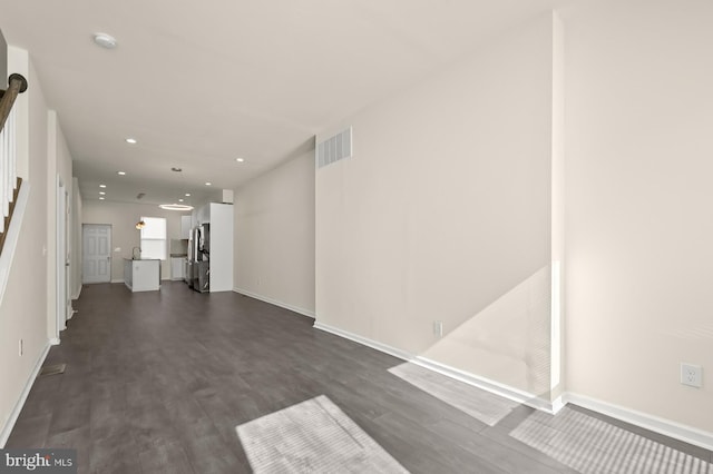 unfurnished living room featuring dark wood finished floors, visible vents, recessed lighting, and baseboards