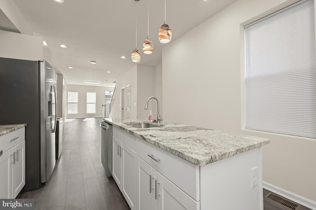 kitchen featuring recessed lighting, stainless steel appliances, a sink, white cabinetry, and a center island with sink