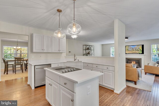 kitchen with dishwasher, black electric stovetop, sink, pendant lighting, and light wood-type flooring