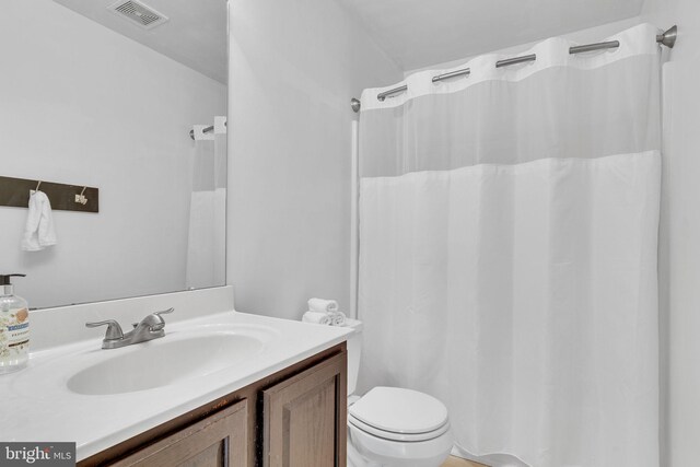 bathroom featuring toilet, curtained shower, and vanity