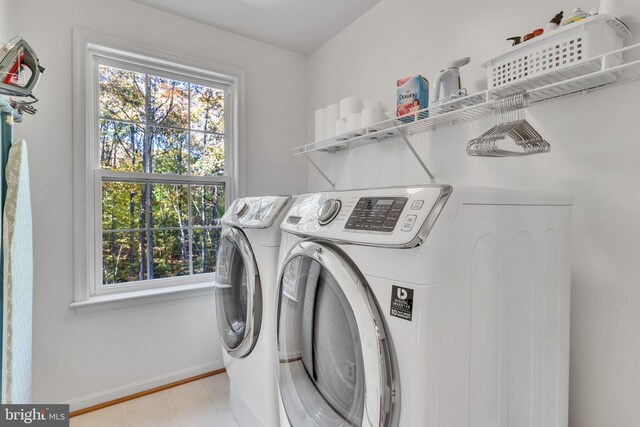 laundry area with independent washer and dryer and light tile patterned floors