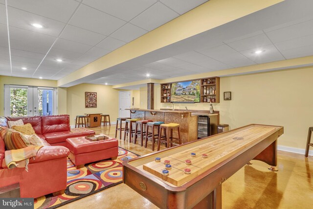 living room featuring a paneled ceiling, wine cooler, and bar area