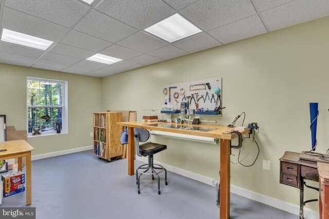 home office featuring a paneled ceiling and concrete flooring