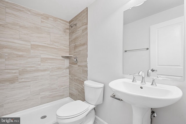 bathroom with toilet, sink, and tiled shower