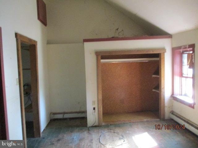 interior space with baseboard heating, hardwood / wood-style floors, and lofted ceiling