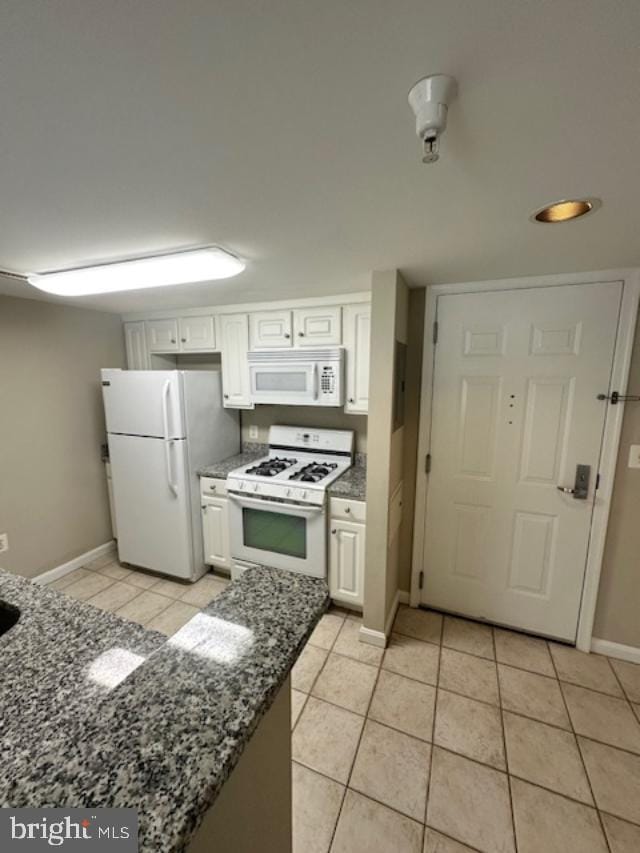 kitchen featuring white cabinets, dark stone countertops, white appliances, and light tile patterned floors