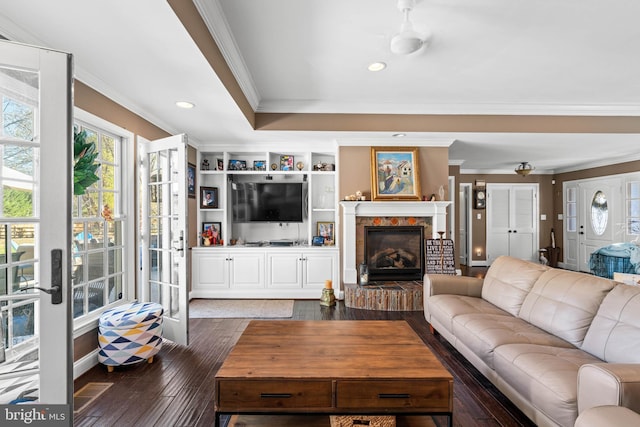 living room featuring dark hardwood / wood-style floors, crown molding, and a brick fireplace