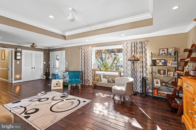 sitting room with dark hardwood / wood-style flooring, a raised ceiling, and ornamental molding