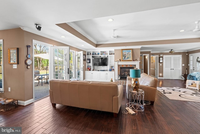 living room featuring ceiling fan, a raised ceiling, ornamental molding, and dark wood-type flooring