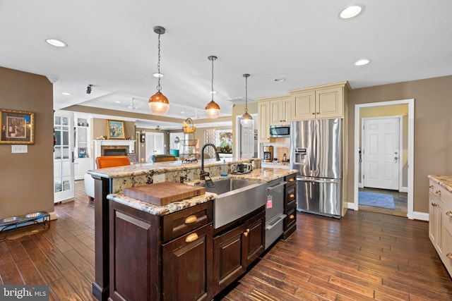 kitchen with dark brown cabinetry, sink, dark wood-type flooring, decorative light fixtures, and appliances with stainless steel finishes