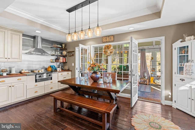 dining space with ornamental molding, a tray ceiling, and dark wood-type flooring