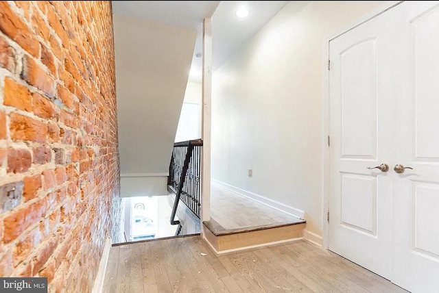 staircase featuring brick wall and wood-type flooring