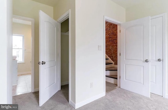 unfurnished bedroom with light carpet and brick wall