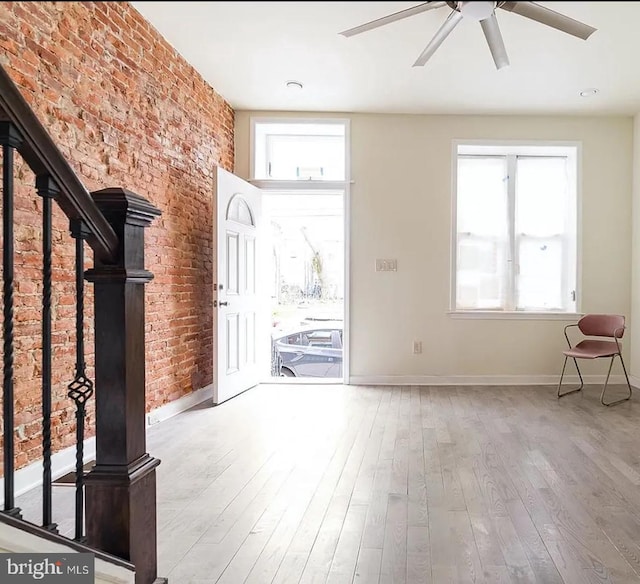 foyer featuring ceiling fan, brick wall, and light wood-type flooring