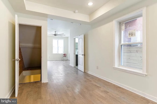 spare room with hardwood / wood-style flooring, a raised ceiling, and ceiling fan