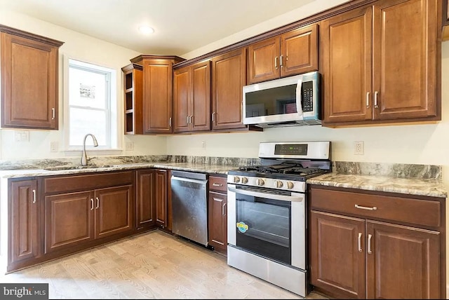 kitchen featuring light stone countertops, sink, light hardwood / wood-style flooring, and stainless steel appliances