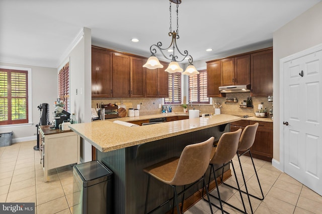 kitchen with backsplash, decorative light fixtures, a kitchen bar, and light tile patterned floors