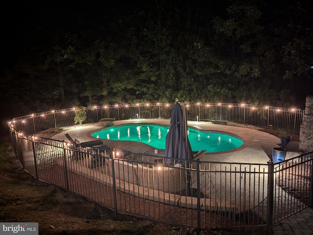 pool at twilight featuring a patio area