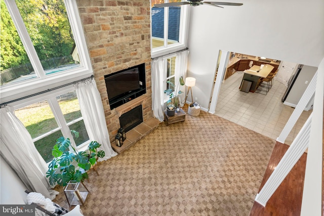 living room featuring tile patterned floors, a stone fireplace, and ceiling fan