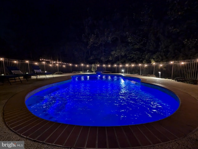 pool at night featuring a patio