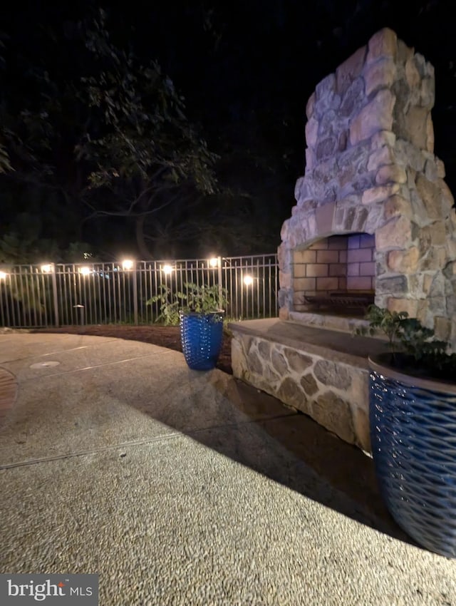 patio at night featuring an outdoor stone fireplace