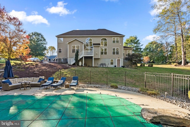 rear view of property featuring a covered pool, a patio, outdoor lounge area, a lawn, and a balcony