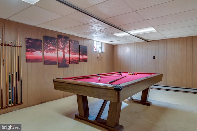 playroom with a paneled ceiling, carpet, a baseboard radiator, and wooden walls