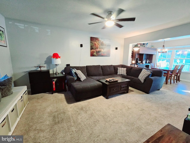 carpeted living room with ceiling fan with notable chandelier