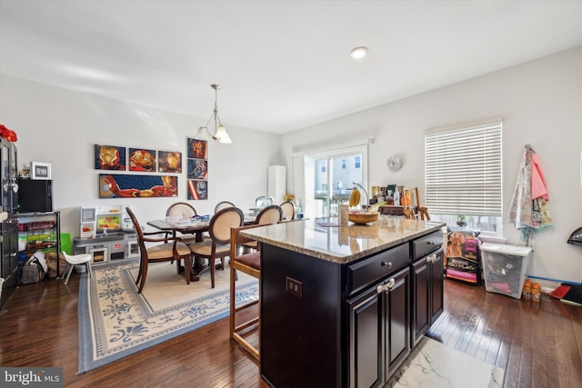 kitchen with decorative light fixtures, a center island, a kitchen bar, and dark hardwood / wood-style flooring