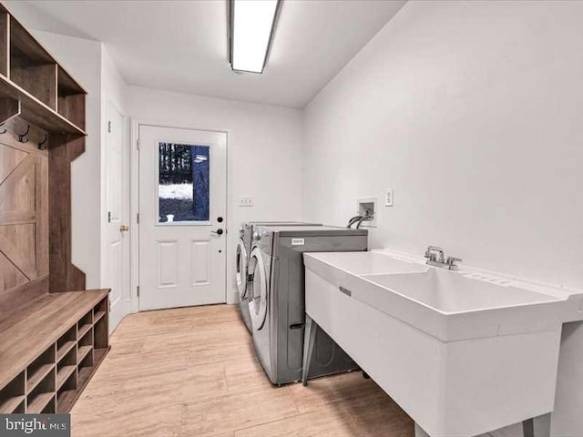 washroom with sink, light hardwood / wood-style floors, and washer and clothes dryer