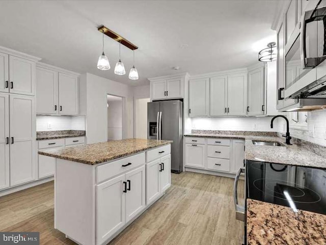 kitchen with a kitchen island, white cabinetry, light hardwood / wood-style flooring, sink, and stainless steel appliances