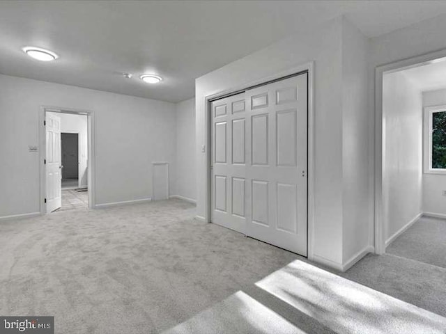 unfurnished bedroom featuring a closet and light colored carpet