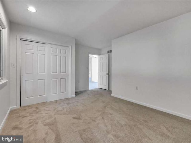 unfurnished bedroom featuring light carpet and a closet