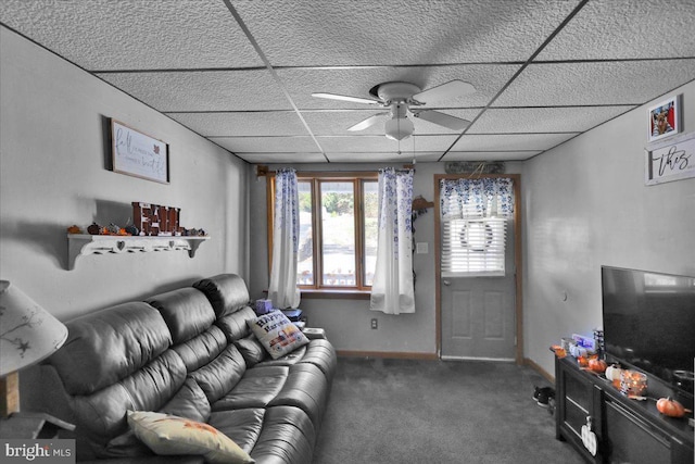 living room with ceiling fan, a drop ceiling, and dark colored carpet