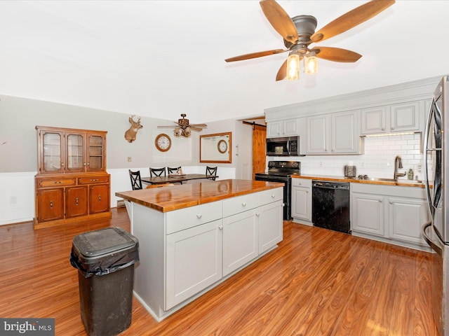 kitchen with light hardwood / wood-style floors, sink, black appliances, white cabinets, and wood counters