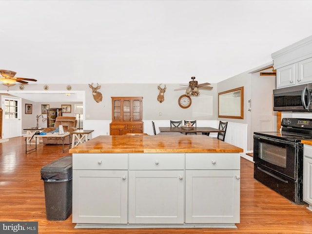 kitchen featuring black electric range, butcher block countertops, and white cabinetry