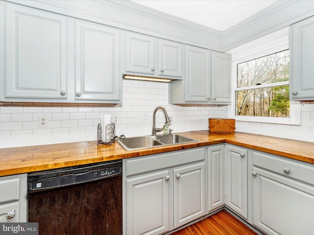 kitchen with black dishwasher, light hardwood / wood-style floors, butcher block countertops, and sink