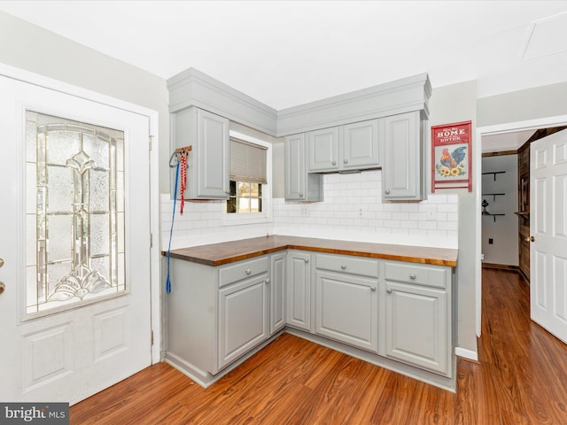 kitchen with light wood-type flooring, butcher block countertops, backsplash, and gray cabinetry