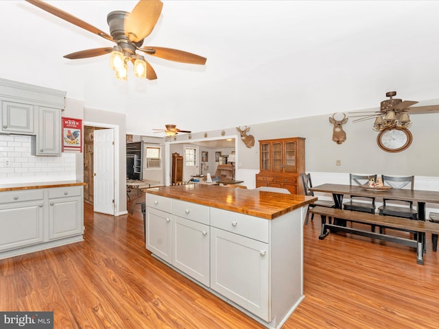 kitchen featuring wooden counters, light hardwood / wood-style flooring, ceiling fan, and tasteful backsplash