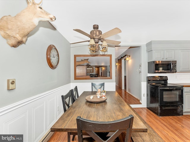 dining room with a barn door, light wood-type flooring, and lofted ceiling