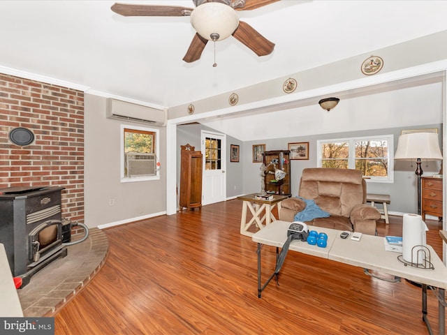 living room featuring a wood stove, a wall unit AC, wood-type flooring, and plenty of natural light