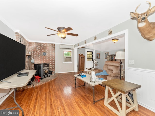 living room featuring a wood stove, crown molding, light wood-type flooring, brick wall, and an AC wall unit