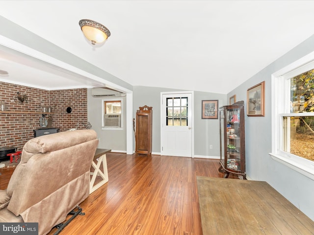 interior space with hardwood / wood-style floors, brick wall, and vaulted ceiling