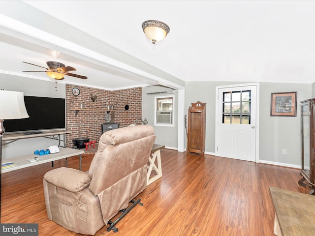 living room with a wood stove, wood-type flooring, brick wall, and ceiling fan