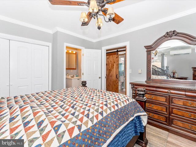 bedroom with ensuite bathroom, a wall mounted AC, crown molding, a closet, and light wood-type flooring