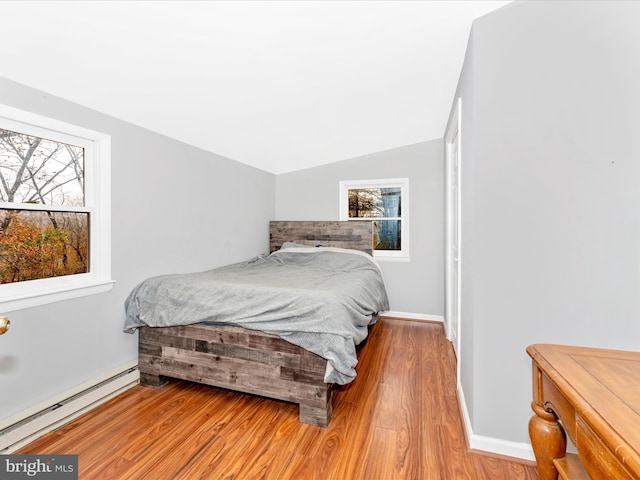 bedroom with light wood-type flooring, multiple windows, a baseboard heating unit, and lofted ceiling