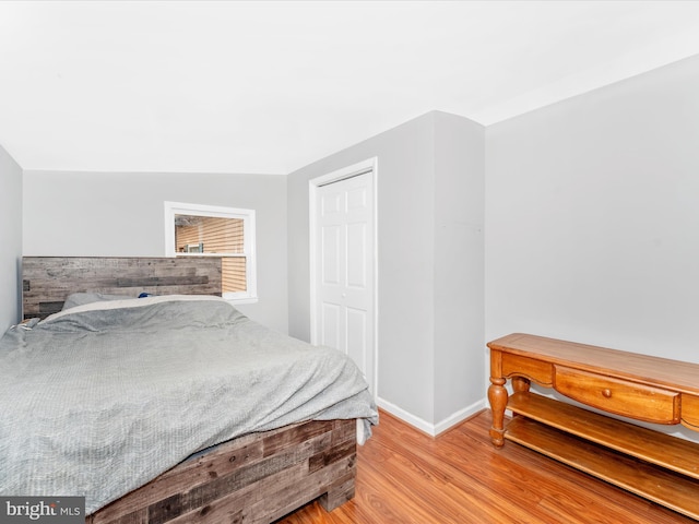 bedroom featuring light hardwood / wood-style flooring, vaulted ceiling, and a closet