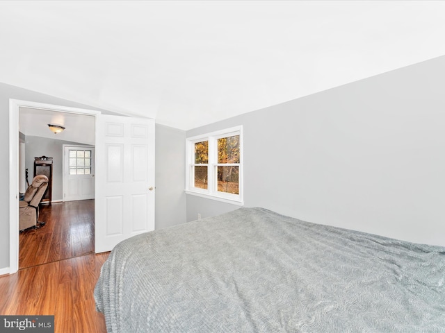 bedroom with hardwood / wood-style flooring, multiple windows, and lofted ceiling