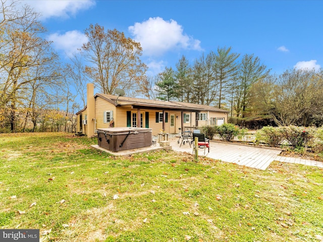 back of property featuring a wooden deck, a yard, and a hot tub