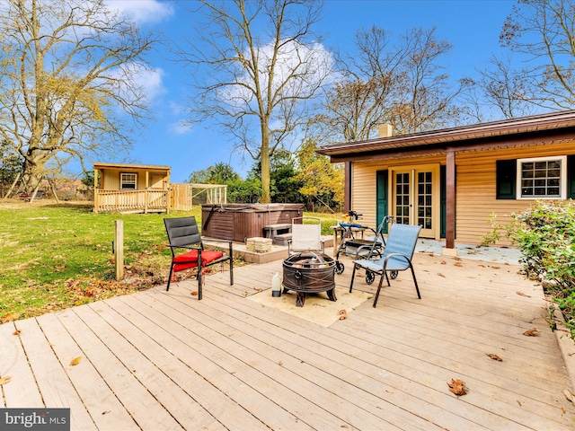 wooden deck featuring an outdoor structure, an outdoor fire pit, and a lawn